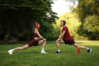 Photo of Happy couple in headphones doing morning exercises in park