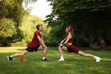 Photo of Happy couple in headphones doing morning exercises in park