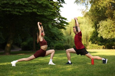 Photo of Happy couple in headphones doing morning exercises in park