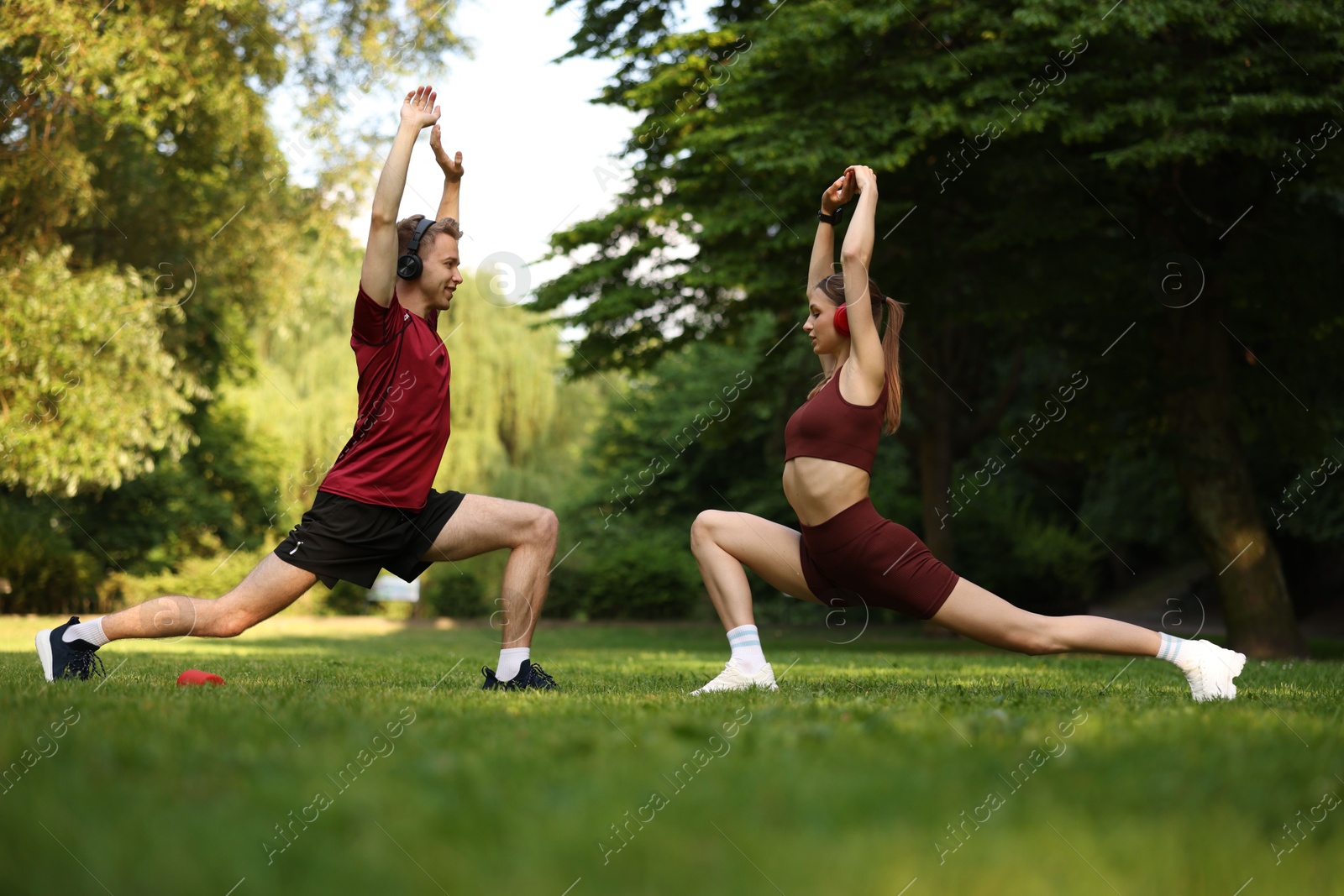 Photo of Happy couple in headphones doing morning exercises in park