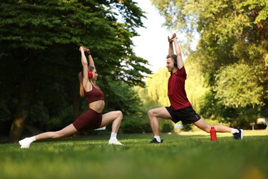 Photo of Happy couple in headphones doing morning exercises in park