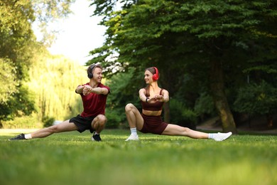 Photo of Happy couple in headphones doing morning exercises in park