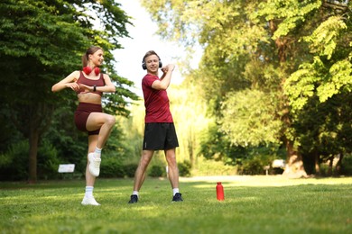 Photo of Happy couple in headphones doing morning exercises in park, low angle view