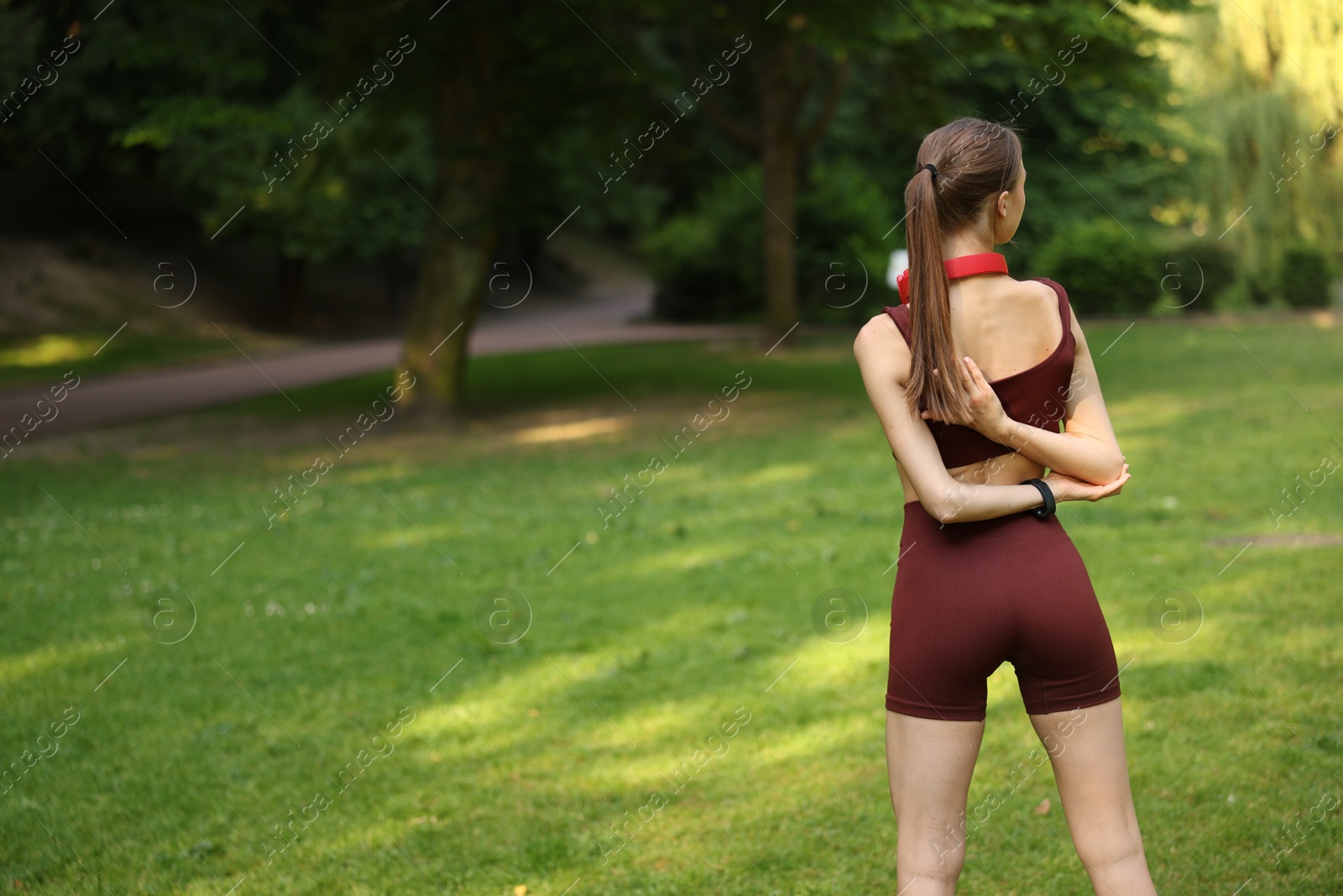 Sportswoman doing morning exercise in park, back view. Space for text Photo of Sportswoman doing morning exercise in park, back view. Space for text