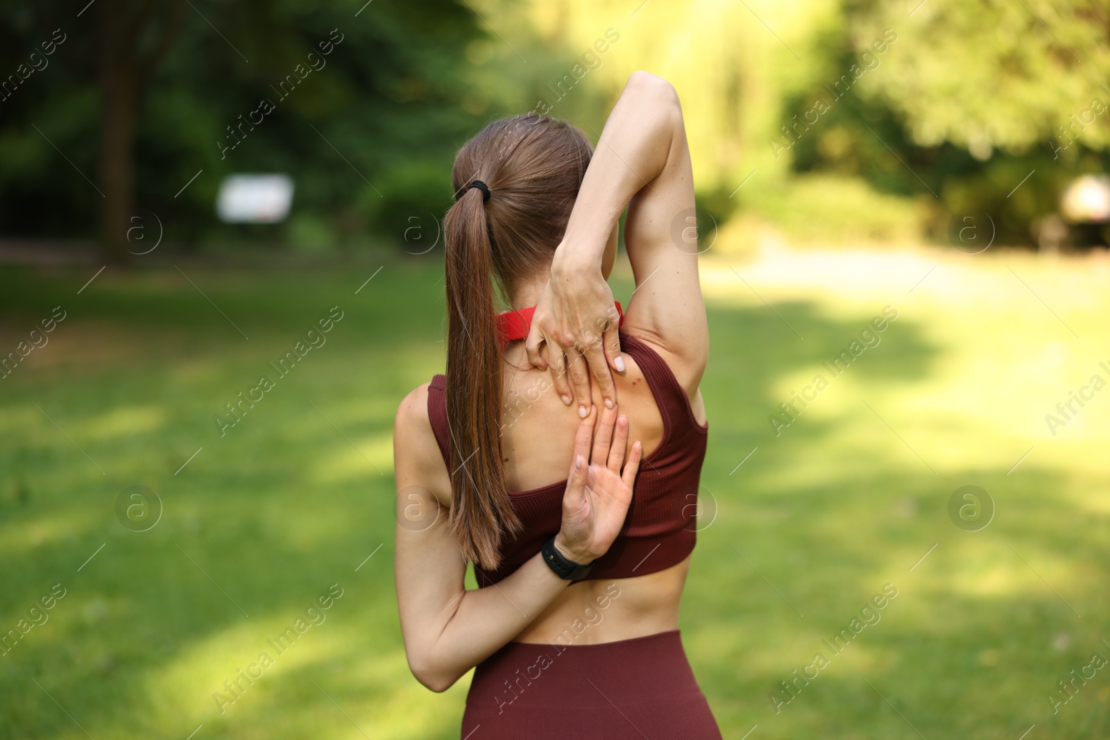 Photo of Sportswoman doing morning exercise in park, back view