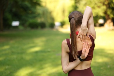 Photo of Sportswoman doing morning exercise in park, back view. Space for text