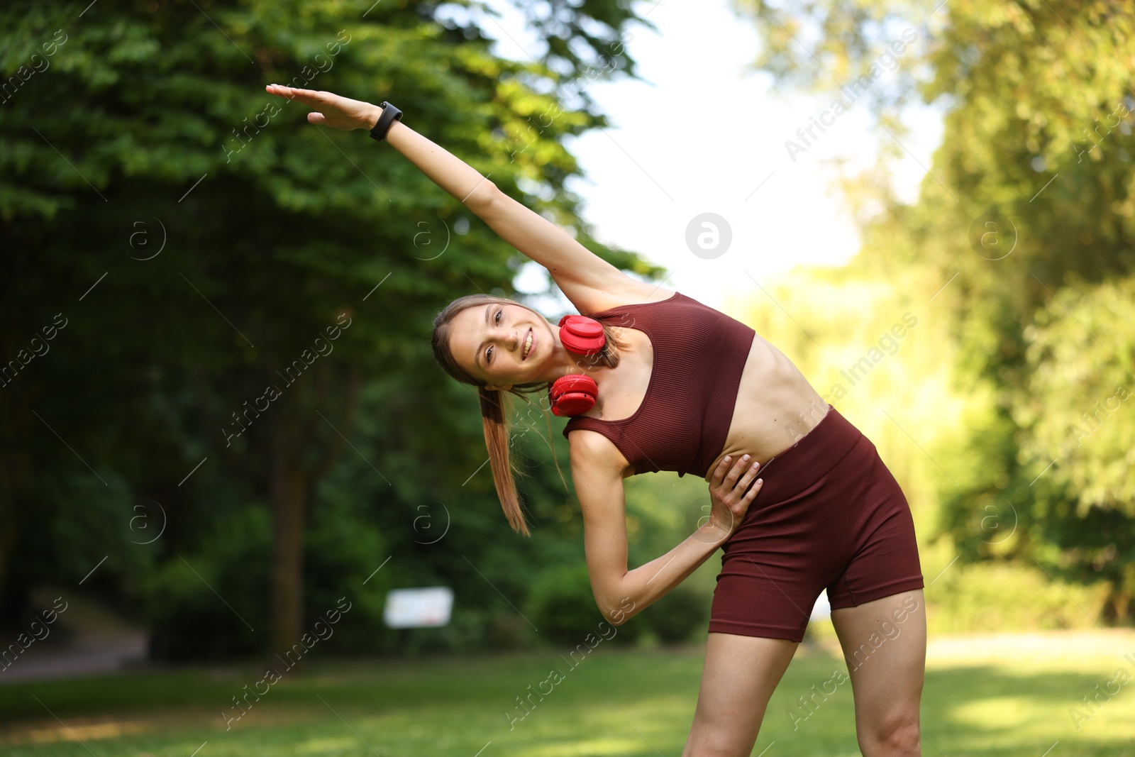 Smiling sportswoman doing morning exercise in park Photo of Smiling sportswoman doing morning exercise in park