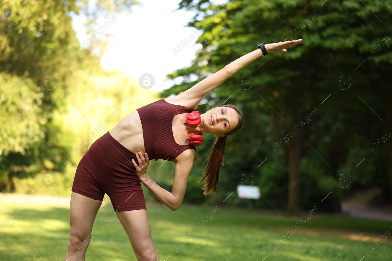 Smiling sportswoman doing morning exercise in park Photo of Smiling sportswoman doing morning exercise in park