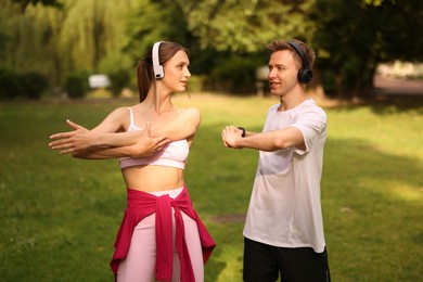 Photo of Happy couple in headphones doing morning exercises in park