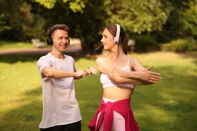 Photo of Happy couple in headphones doing morning exercises in park
