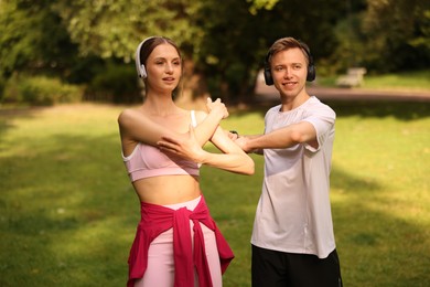 Photo of Happy couple in headphones doing morning exercises in park