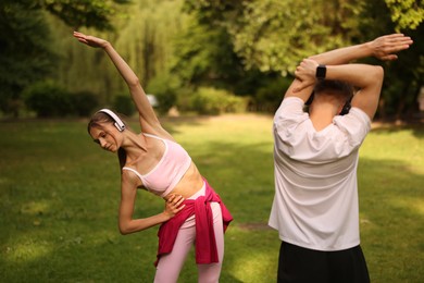 Photo of Couple in headphones doing morning exercises in park