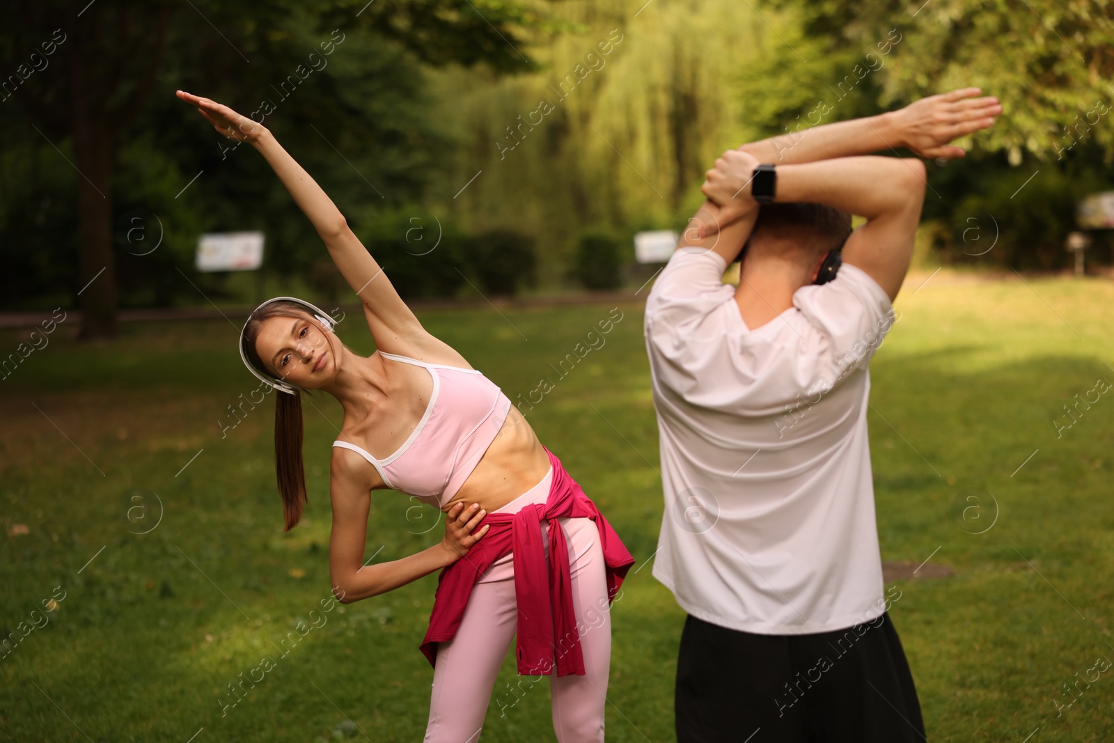 Couple in headphones doing morning exercises in park Photo of Couple in headphones doing morning exercises in park