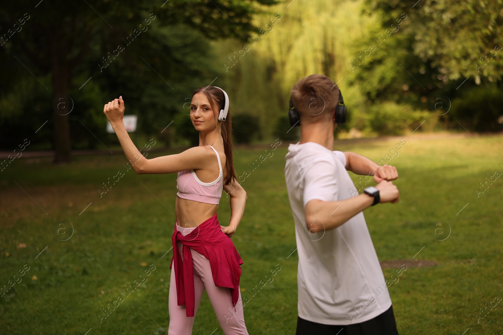 Photo of Couple in headphones doing morning exercises in park