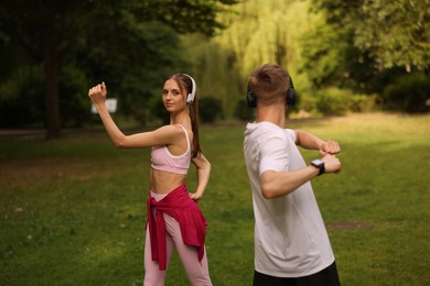 Photo of Couple in headphones doing morning exercises in park
