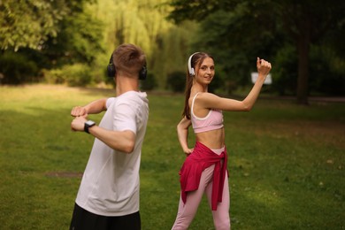 Photo of Couple in headphones doing morning exercises in park