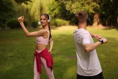 Photo of Couple in headphones doing morning exercises in park