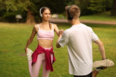 Photo of Couple in headphones doing morning exercises in park