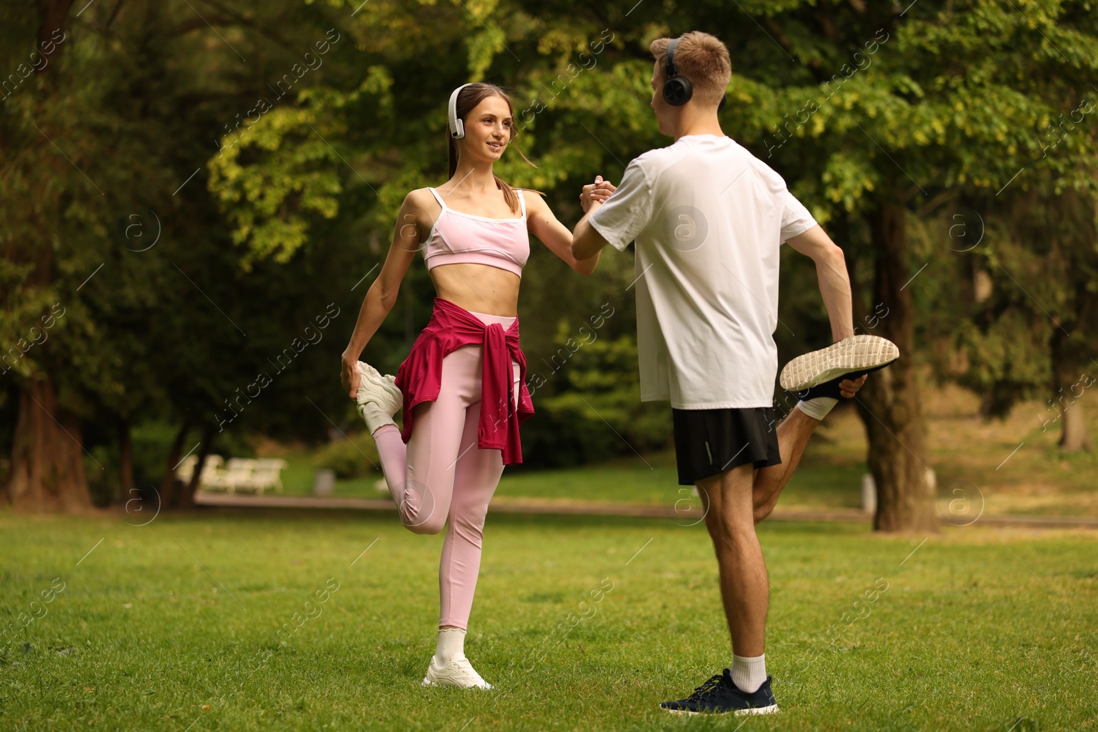 Couple in headphones doing morning exercise in park Photo of Couple in headphones doing morning exercise in park