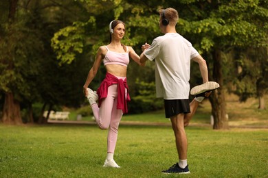 Photo of Couple in headphones doing morning exercise in park