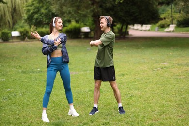 Photo of Happy couple in headphones doing morning exercises in park