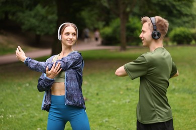 Photo of Happy couple in headphones doing morning exercises in park