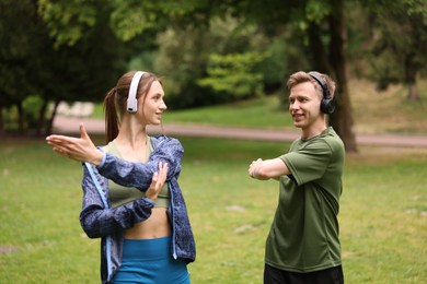 Photo of Happy couple in headphones doing morning exercises in park