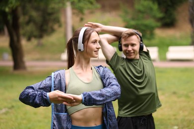 Photo of Happy couple in headphones doing morning exercises in park