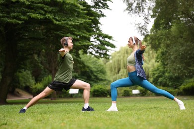 Photo of Happy couple in headphones doing morning exercises in park