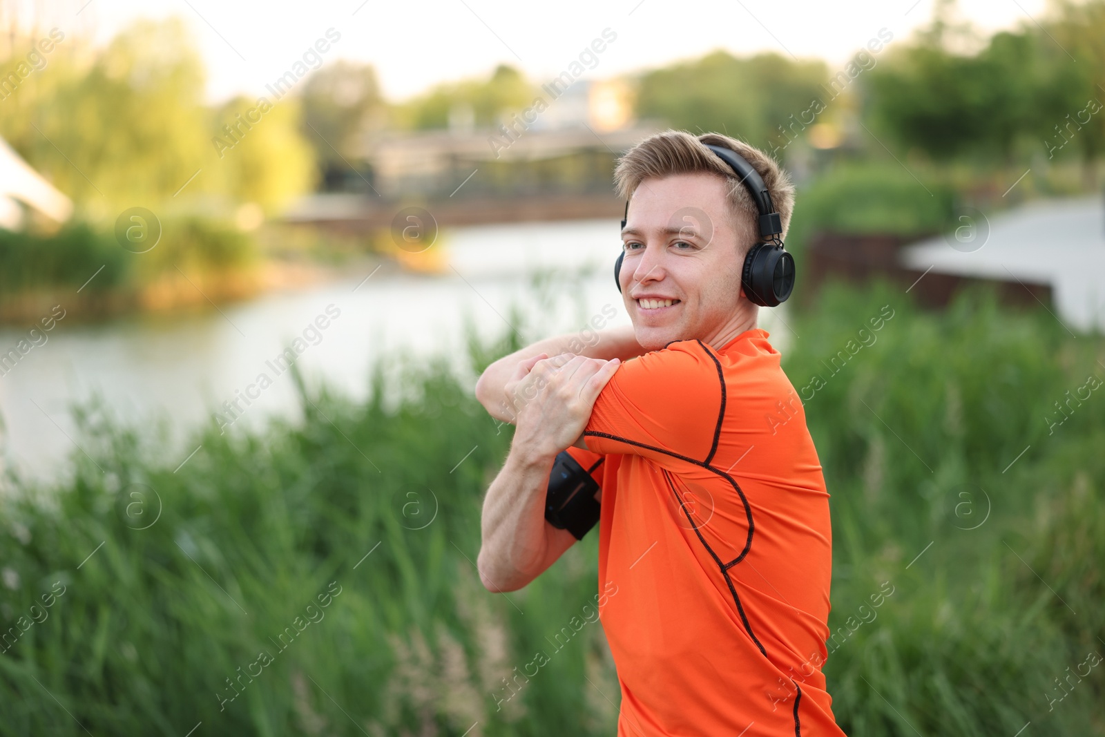 Smiling sportsman in headphones doing morning exercise outdoors Photo of Smiling sportsman in headphones doing morning exercise outdoors