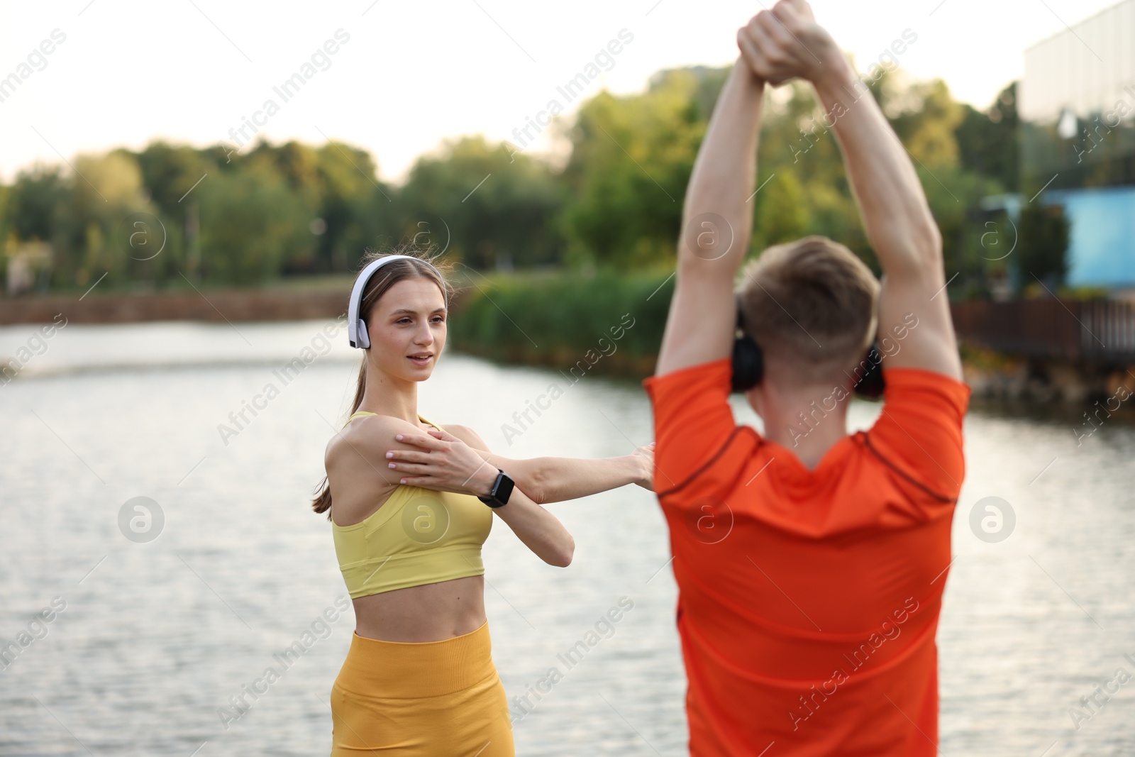 Couple in headphones doing morning exercise near river Photo of Couple in headphones doing morning exercise near river