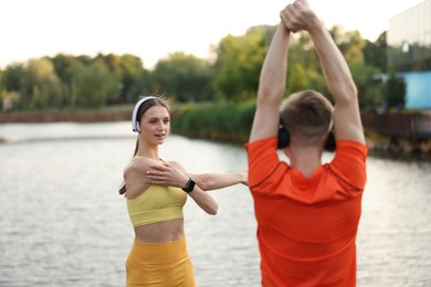 Photo of Couple in headphones doing morning exercise near river