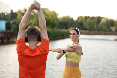 Photo of Couple in headphones doing morning exercise near river