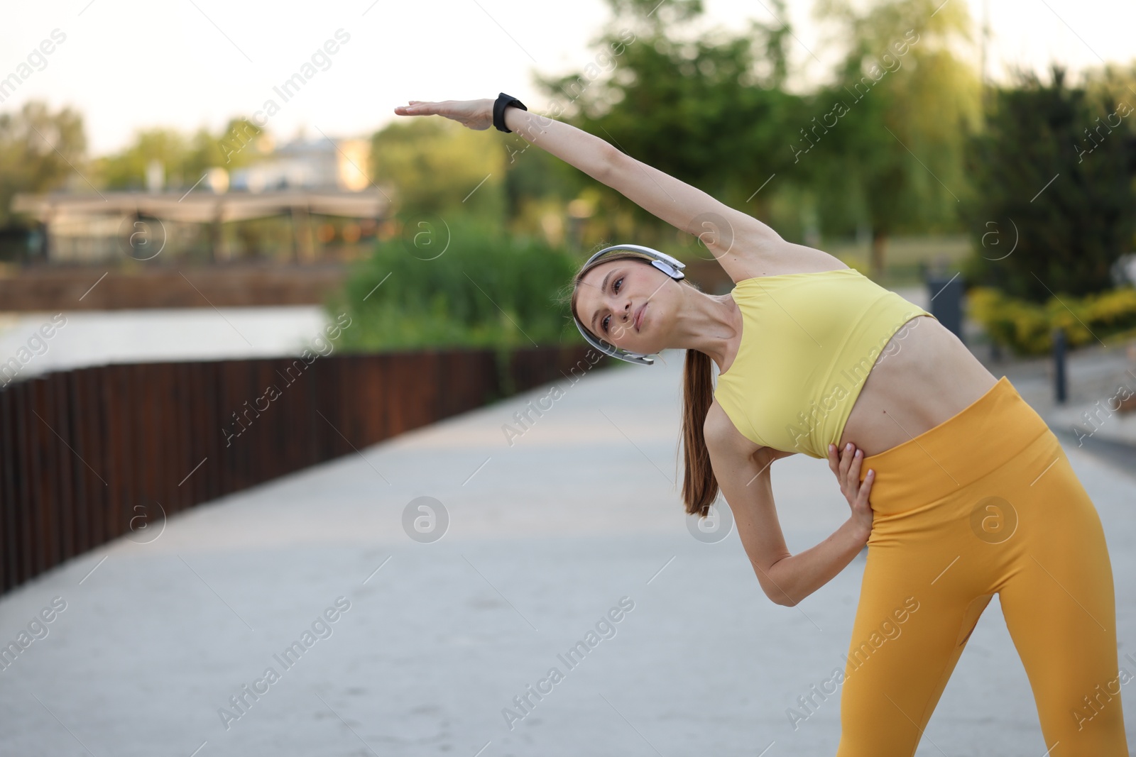 Young sportswoman in headphones doing morning exercise outdoors. Space for text Photo of Young sportswoman in headphones doing morning exercise outdoors. Space for text