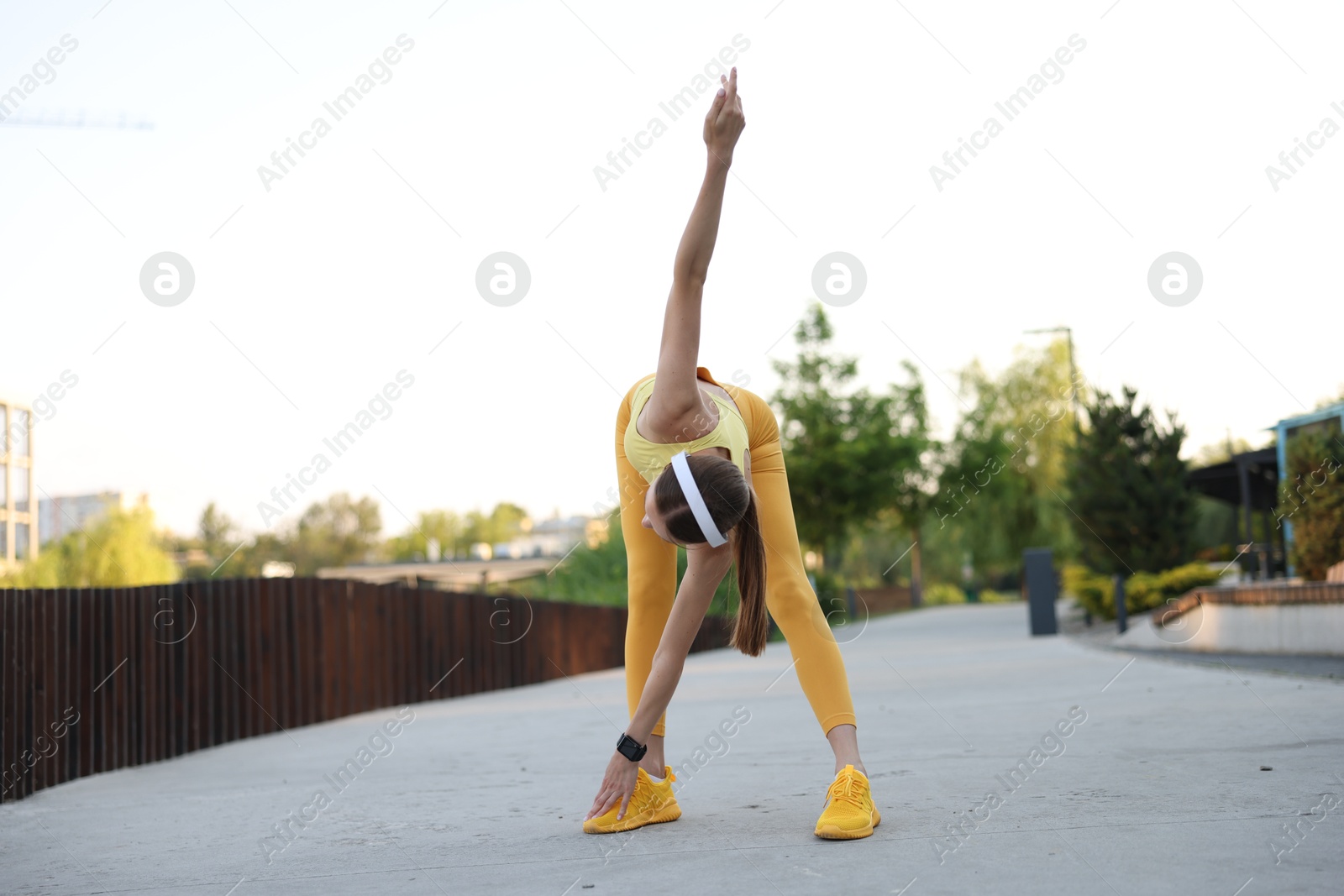 Young sportswoman in headphones doing morning exercise outdoors Photo of Young sportswoman in headphones doing morning exercise outdoors