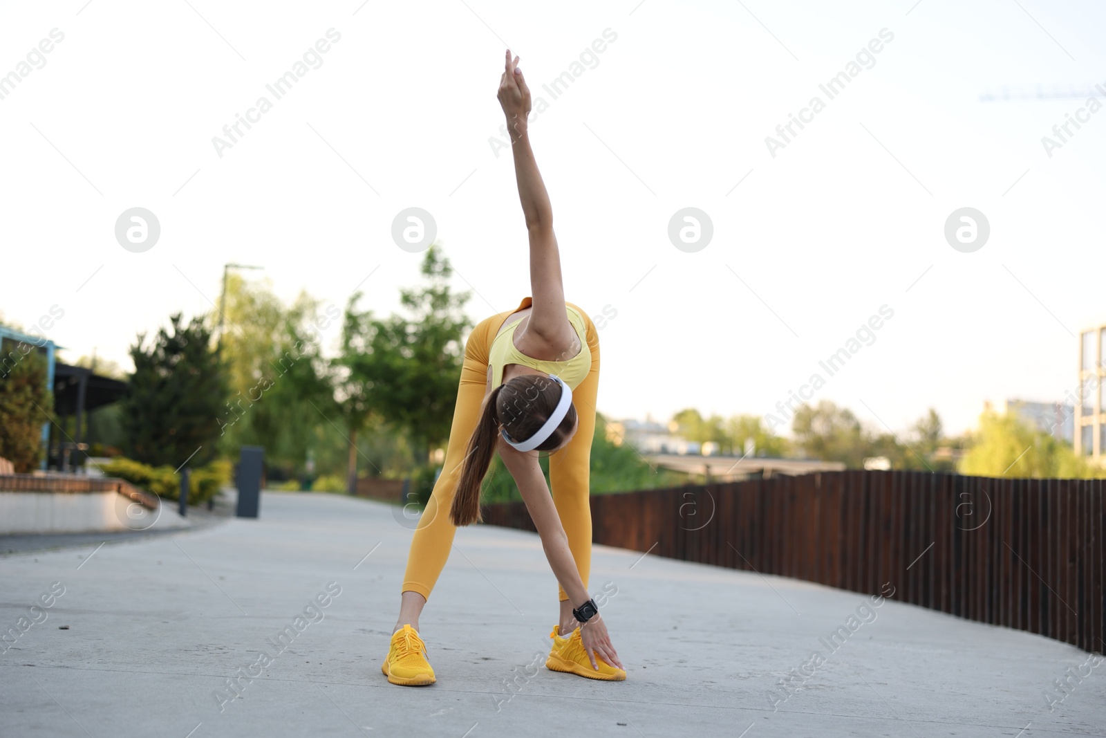 Young sportswoman in headphones doing morning exercise outdoors Photo of Young sportswoman in headphones doing morning exercise outdoors
