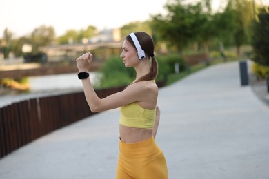 Photo of Young sportswoman in headphones doing morning exercise outdoors