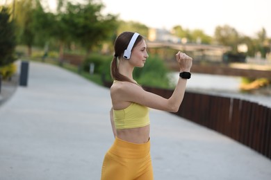 Photo of Young sportswoman in headphones doing morning exercise outdoors