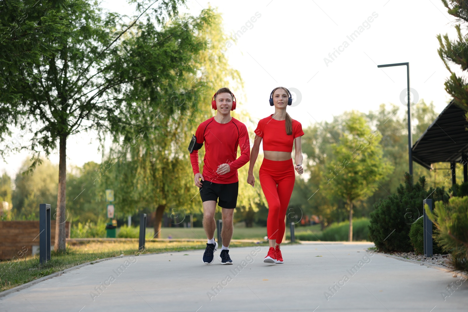 Happy couple in headphones running outdoors, low angle view. Morning exercise Photo of Happy couple in headphones running outdoors, low angle view. Morning exercise