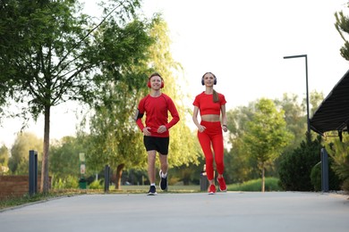Photo of Happy couple in headphones running outdoors, low angle view. Morning exercise