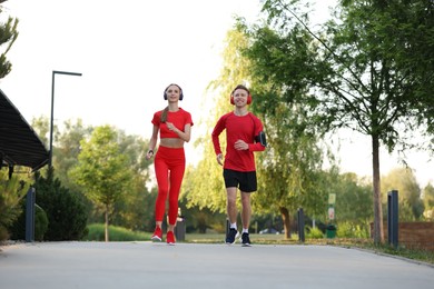 Photo of Happy couple in headphones running outdoors, low angle view. Morning exercise