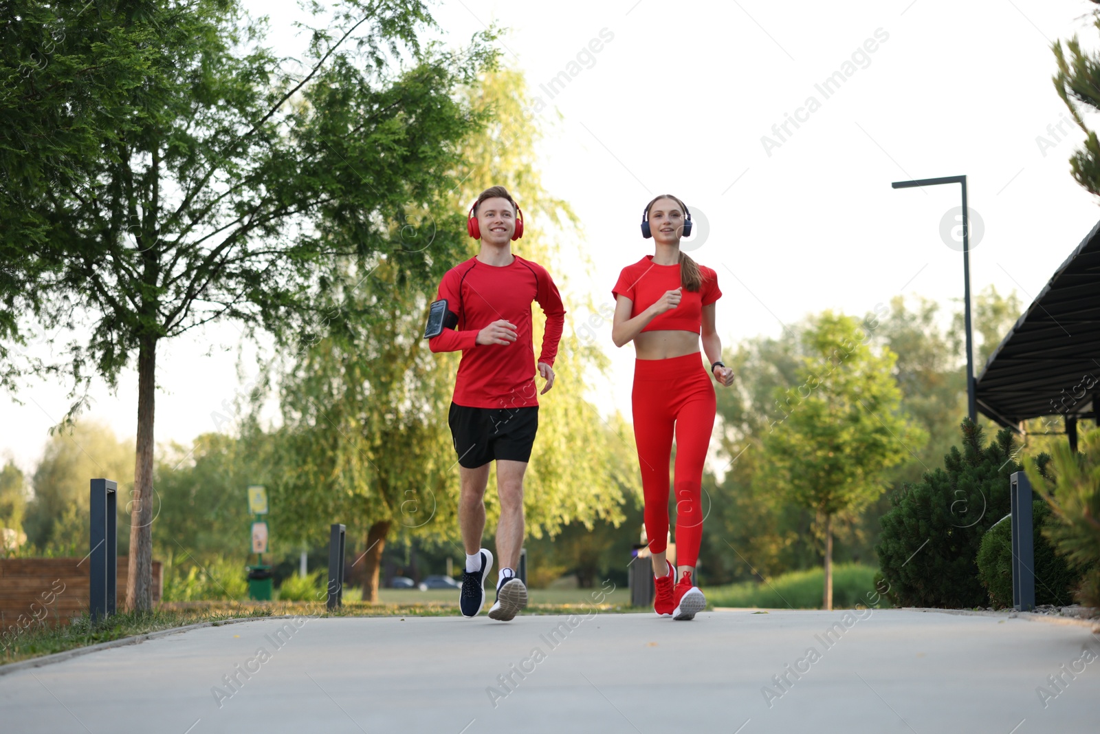 Happy couple in headphones running outdoors, low angle view. Morning exercise Photo of Happy couple in headphones running outdoors, low angle view. Morning exercise