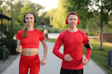 Photo of Happy couple in headphones running outdoors. Morning exercise