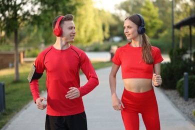 Photo of Happy couple in headphones running outdoors. Morning exercise