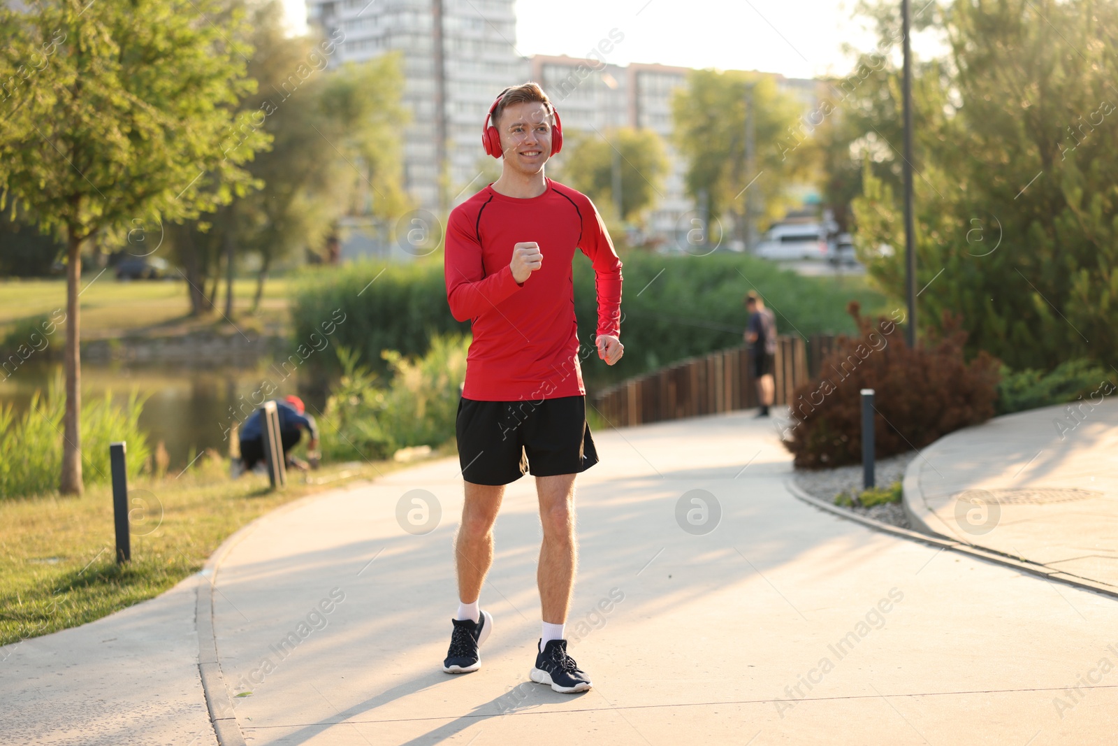 Smiling sportsman in headphones running outdoors. Morning exercise Photo of Smiling sportsman in headphones running outdoors. Morning exercise