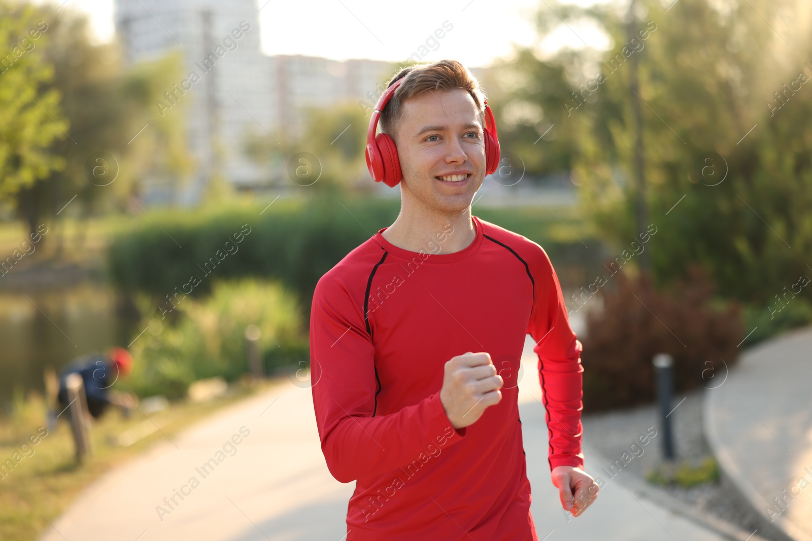 Smiling sportsman in headphones running outdoors. Morning exercise Photo of Smiling sportsman in headphones running outdoors. Morning exercise