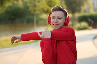 Photo of Smiling sportsman in headphones doing morning exercise outdoors. Healthy lifestyle