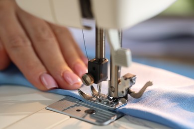 Photo of Woman working with sewing machine on blurred background, macro view