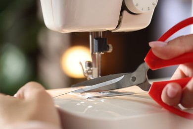 Photo of Woman working with sewing machine on blurred background, macro view