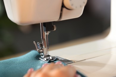 Photo of Woman working with sewing machine on blurred background, macro view
